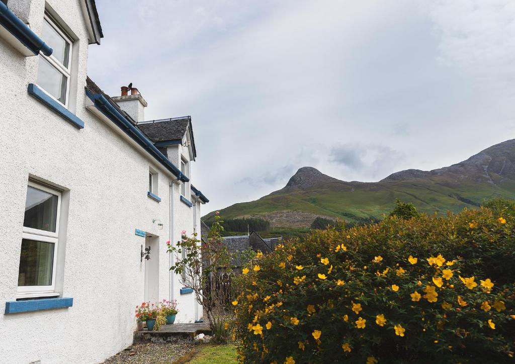 Duart Cottage white traditional exterior in Glencoe Village with mountain background
