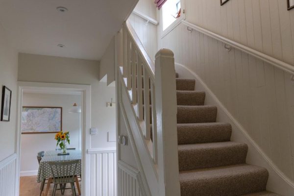 Traditional hallway with carpeted stairs leading to upper bedrooms at Duart Cottage