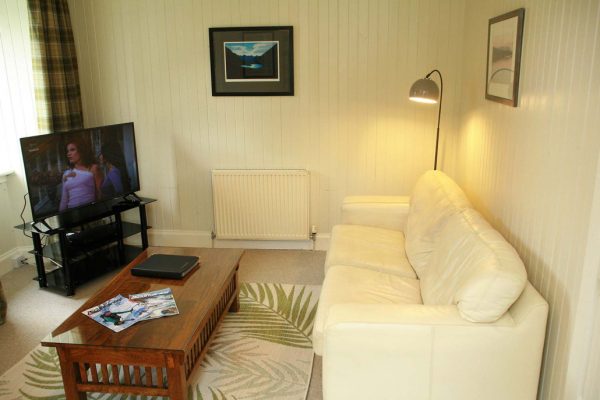 Cozy living room lounge with fireplace, comfortable sofa, and TV at Duart Cottage